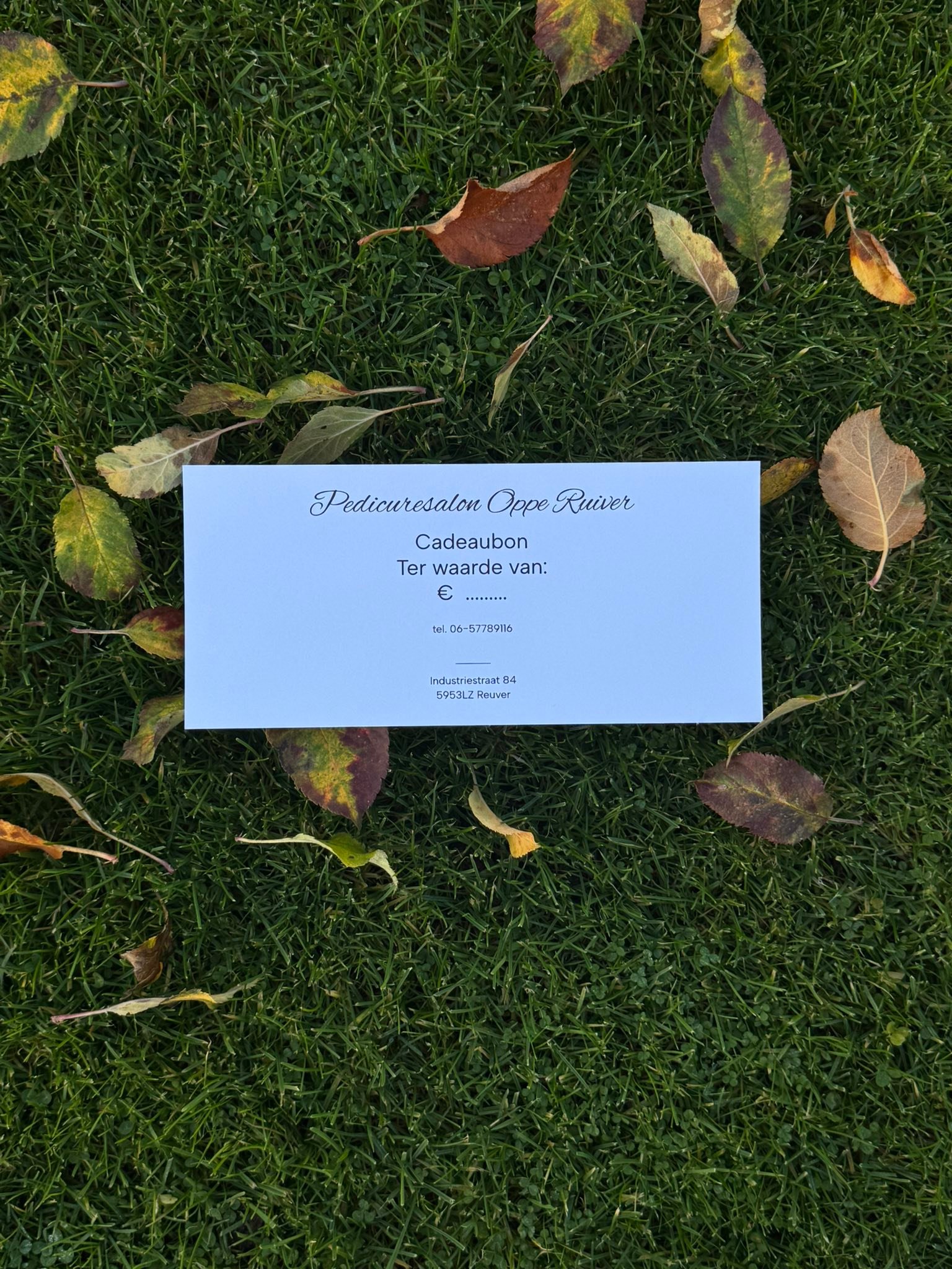De cadeaubon van Pedicuresalon Oppe Ruiver op het gras tussen herfstbladeren