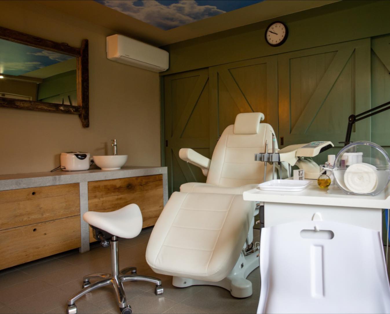 De hele behandelkamer met groene schuifdeuren, de pedicurestoel en een wastafel op een betonnen blad